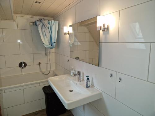 a bathroom with a sink and a mirror and a tub at Ferienwohnung Blumenshein bei Speyer Karlsruhe Familienfreundlich 5 Pers in Zeiskam