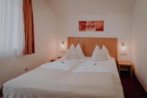 a bedroom with a large bed with white sheets at Sporthotel Kitz in Bruck an der Großglocknerstraße