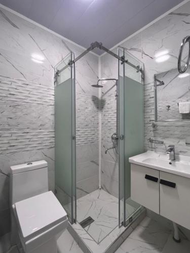 a bathroom with a shower and a toilet and a sink at Oqshom Plaza Hotel in Qarshi