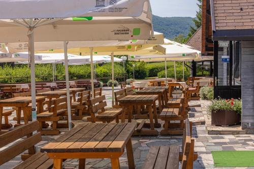 a restaurant with wooden tables and umbrellas on a patio at Bungalows Korana - Campsite Korana in Seliste Dreznicko