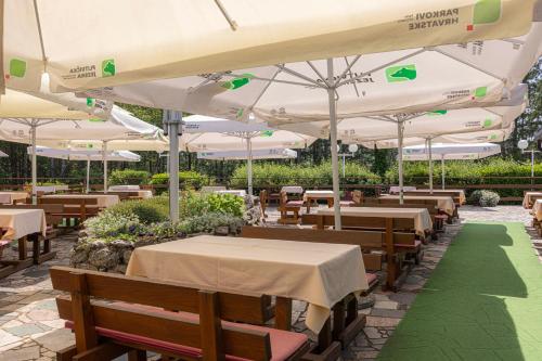 a restaurant with tables and chairs and umbrellas at Bungalows Korana - Campsite Korana in Seliste Dreznicko