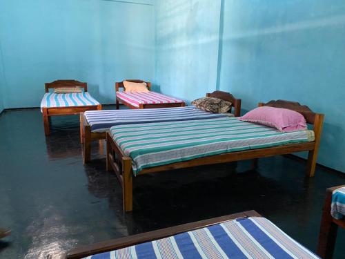 3 camas en una habitación con paredes azules en Moon Eyes Beach Hotel, en Arugam Bay