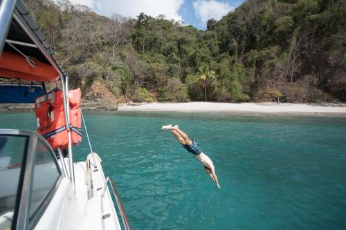 a man diving into the water from a boat at Hotel Nya in Montezuma