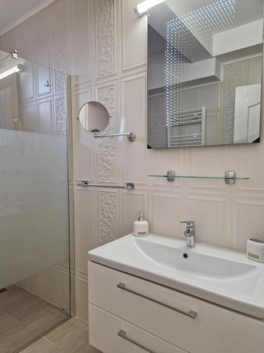 uma casa de banho branca com um lavatório e um chuveiro em Caprice Deluxe Accomodation em Drobeta-Turnu Severin