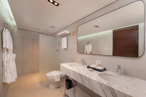 a bathroom with two sinks and a toilet and a mirror at The Belamy House Managed by HII in Manila
