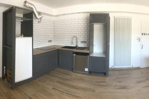 - une cuisine avec des placards noirs et un mur blanc dans l'établissement Chambre dans logement neuf et tout équipé RDC, à Felletin