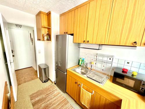 a kitchen with wooden cabinets and a stainless steel refrigerator at Renovated Charming Apt Ideal to visit Paris in Clichy