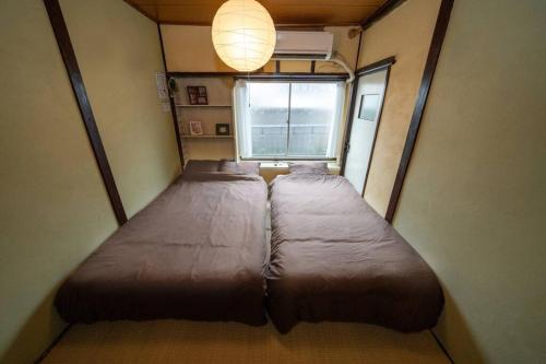 Cama grande en habitación pequeña con ventana en I LOVE OSAKA, en Osaka