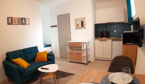 uma sala de estar com um sofá azul e uma cozinha em Les Studio Cosy - Lunéville centre em Lunéville