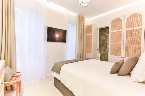 une chambre blanche avec un lit et une télévision dans l'établissement Luxueuse Villa 7 chambres avec piscine - Cannes, à Cannes
