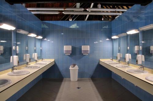 a blue tiled bathroom with a row of sinks at Bungalows Korana - Campsite Korana in Seliste Dreznicko