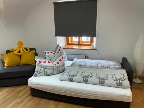 ein Schlafzimmer mit einem Bett mit Kissen und einem Sofa in der Unterkunft Ferienwohnung Sommeralm in Arzberg