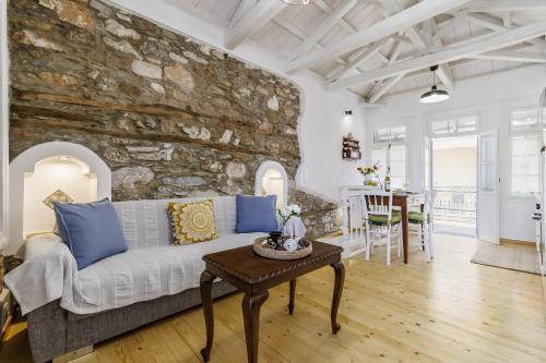 AIKATERINI'S House في سكوبيلوس تاون: غرفة معيشة مع جدار حجري وأريكة