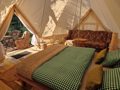 a bedroom with a tent with a bed and a couch at Glamping Štôla- Symbioza in Štôla