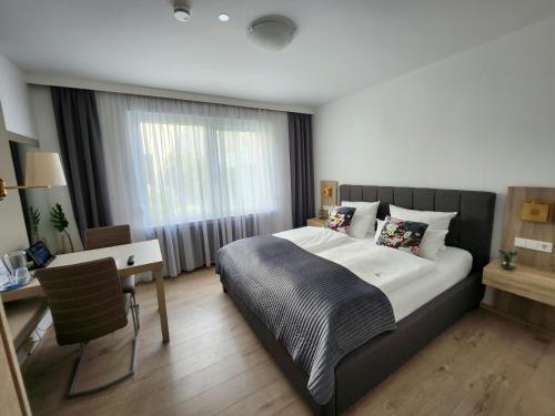 a bedroom with a bed and a desk and a window at Stadthotel Geis in Bad Neustadt an der Saale