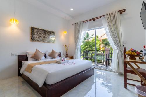 a bedroom with a large bed and a balcony at Angkor Rithy Boutique Group in Siem Reap