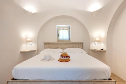 ein Schlafzimmer mit einem weißen Bett mit zwei Hüten darauf in der Unterkunft Trullo Encanto with pool in Ceglie Messapica