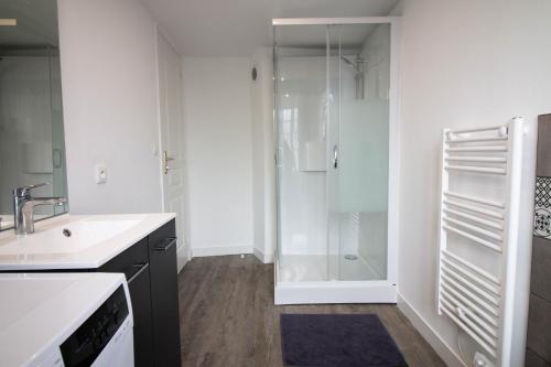 een witte badkamer met een wastafel en een douche bij Home2Stay Valognes in Valognes