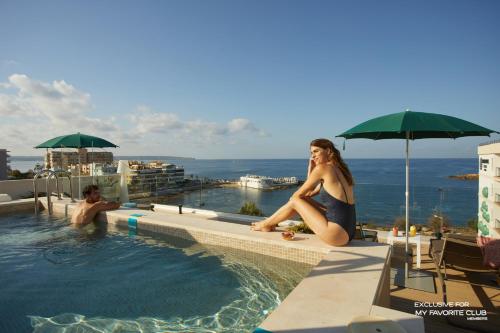 a woman sitting on the edge of a swimming pool at AluaSoul Palma Hotel Adults Only in Can Pastilla