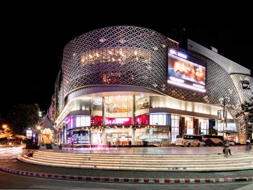 a large building with a curved facade at night at Dominol House l 5 min to Nimman l MAYA l Old Town l 附近的房子 in Chiang Mai