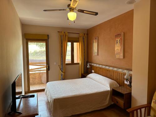 1 dormitorio con 1 cama y ventilador de techo en Hotel Restaurante Los Caños de la Alcaiceria en Alhama de Granada