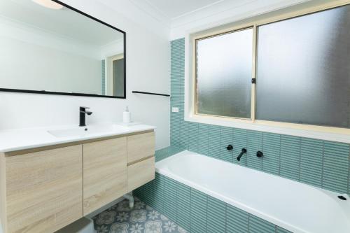 un bagno con vasca, lavandino e finestra di 10 Minnibah Circuit a Forster