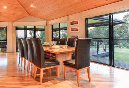 a dining room with a wooden table and black chairs at Shumadia I Private Properties in Yallingup Siding