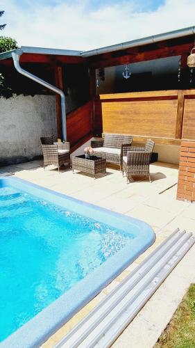 a swimming pool with two chairs and a table at Ferienzimmer Kefeder in Lochenhaus