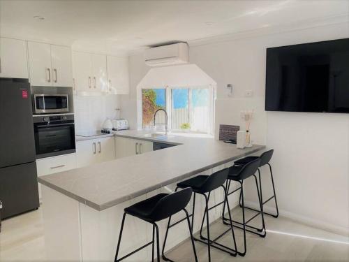 a kitchen with a counter with four bar stools at Salt & Soul Beach Shack in Esperance