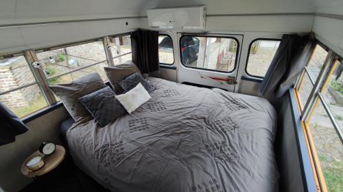 a bed in the back of a van with windows at The School Bus in Bassenge