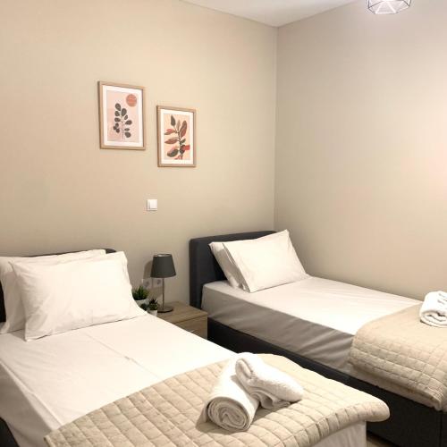 a room with two beds with white sheets and towels at Lilium Luxury Apartment in Igoumenitsa