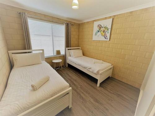 a small bedroom with two beds and a window at Sea Stays Esperance in Esperance