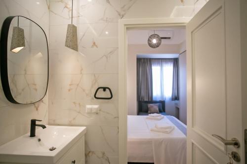 Un baño con lavabo, espejo y cama. en Thalia by Heloni Apartments, en Atenas