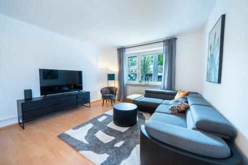 a living room with a couch and a tv at Coblenz Suites - Design Apartment City - 2 Bedrooms in Koblenz