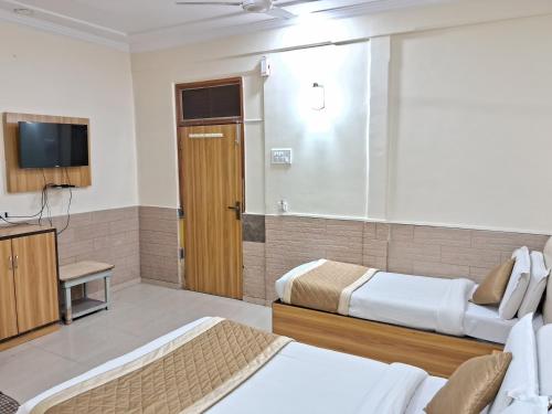 a hotel room with two beds and a television at Swapna International in Mumbai