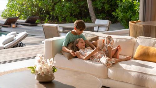 a boy and a girl laying on a couch at The Ritz-Carlton Maldives, Fari Islands in North Male Atoll