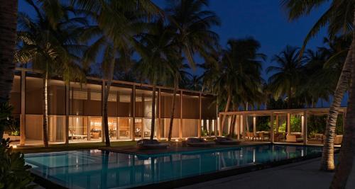 a building with a swimming pool and palm trees at The Ritz-Carlton Maldives, Fari Islands in North Male Atoll