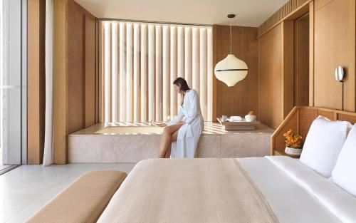 a woman sitting on a window seat in a hotel room at The Ritz-Carlton Maldives, Fari Islands in North Male Atoll