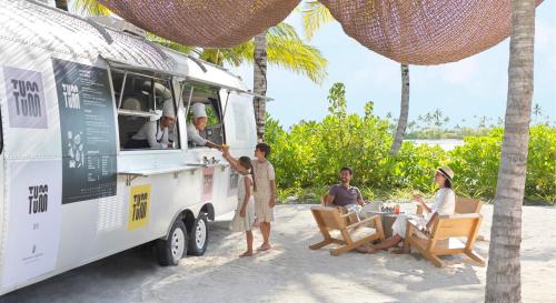 a group of people standing around a food truck on the beach at The Ritz-Carlton Maldives, Fari Islands in North Male Atoll