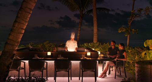 a man sitting in a bath tub on the beach at night at The Ritz-Carlton Maldives, Fari Islands in North Male Atoll