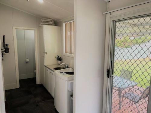 a small kitchen with a sink and a washing machine at Six By The Beach in Esperance