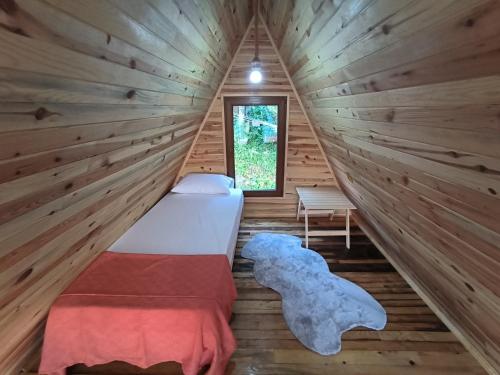 1 dormitorio en una cabaña de madera con cama y ventana en Neyla Suit Bungalow, en Arhavi