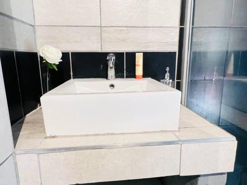 lavabo blanco en el baño con una flor en Affordable Guest Room @260Main en Johannesburgo