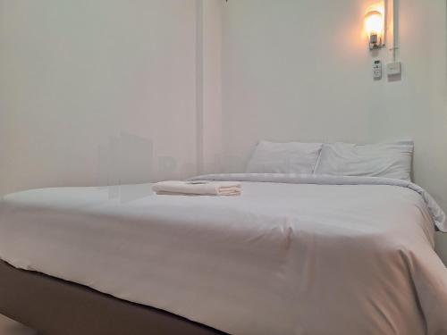 un letto bianco con un asciugamano sopra di Adam Guesthouse Mitra RedDoorz a Bogor