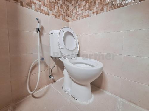 een wit toilet in een badkamer met een douche bij Adam Guesthouse Mitra RedDoorz in Bogor