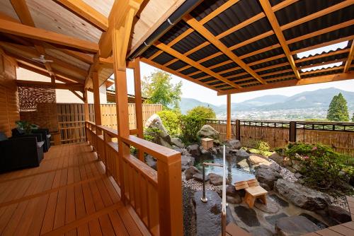 an outdoor deck with a pond and a wooden pergola at Yufuin-Sanso Waremokou in Yufu