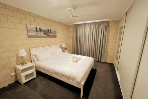 a bedroom with a white bed and a night stand at Stay By The Sea Esperance in Esperance