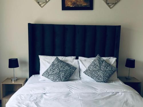 a bed with a blue headboard and pillows on it at Taznet Homes - 3 Bedroomed House in Edenvale