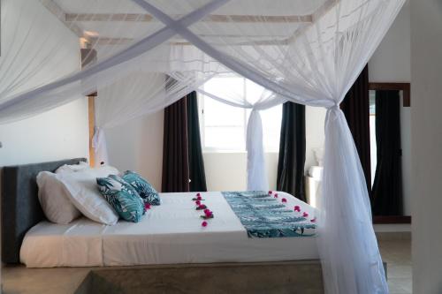 a bedroom with a white bed with a canopy at Visiwa Beach Resort in Watamu