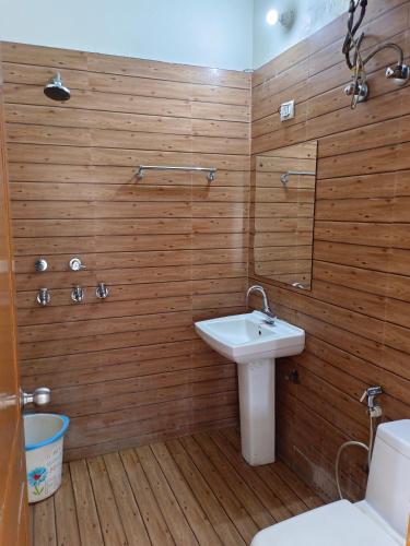a bathroom with wooden walls and a sink and a toilet at Viraj Guest House in Noida